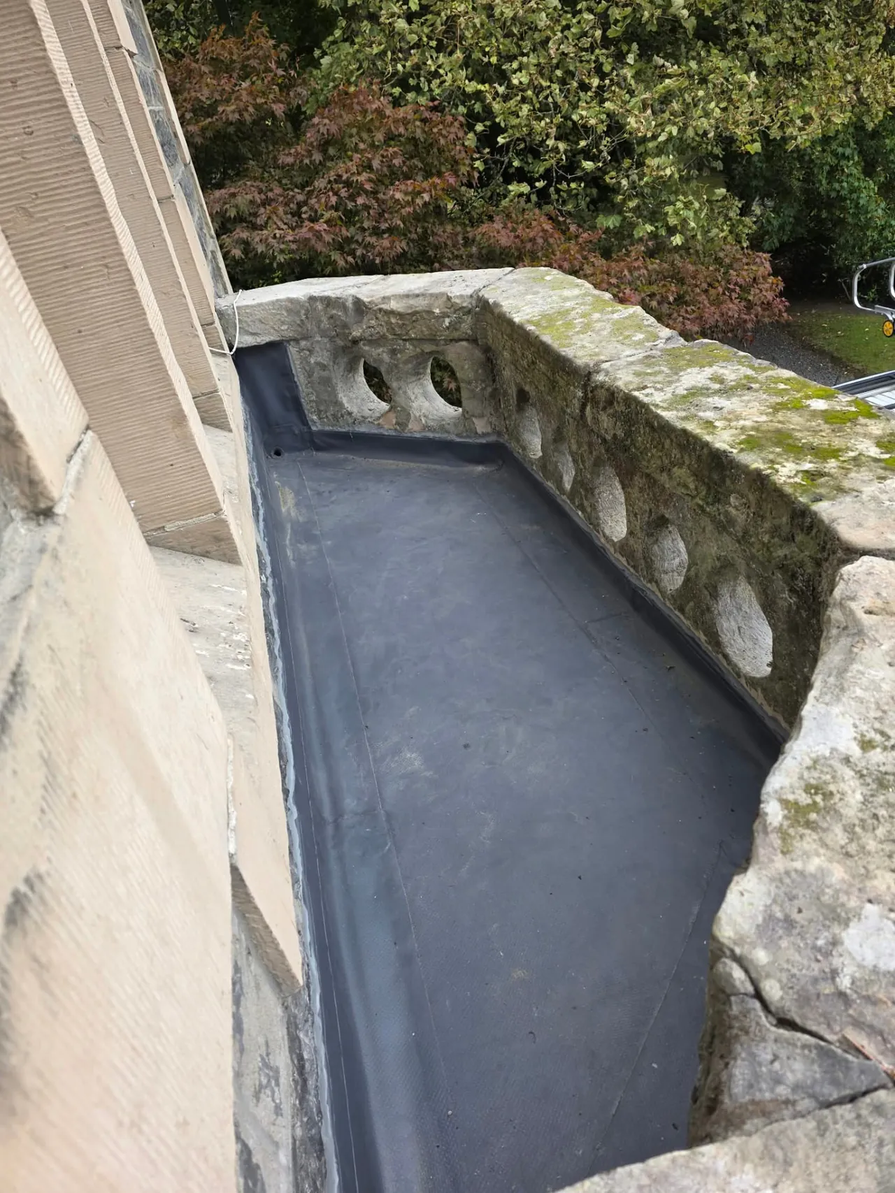 Completed flat roof replacement with a new single-ply membrane behind a stone balustrade in Perthshire