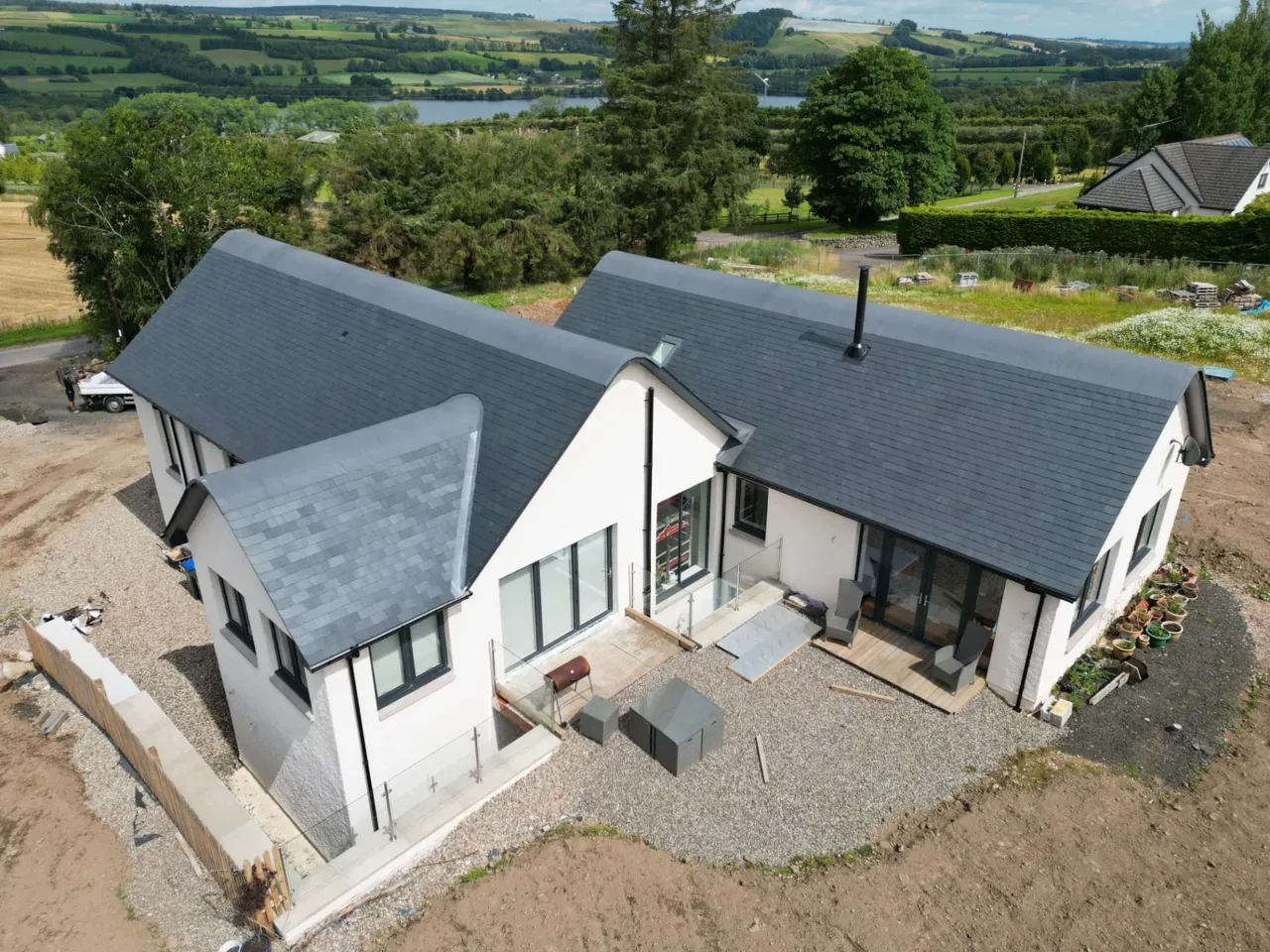 Aerial view of a new slate roof with swept ridges on a Perthshire home by Ericht Roofing