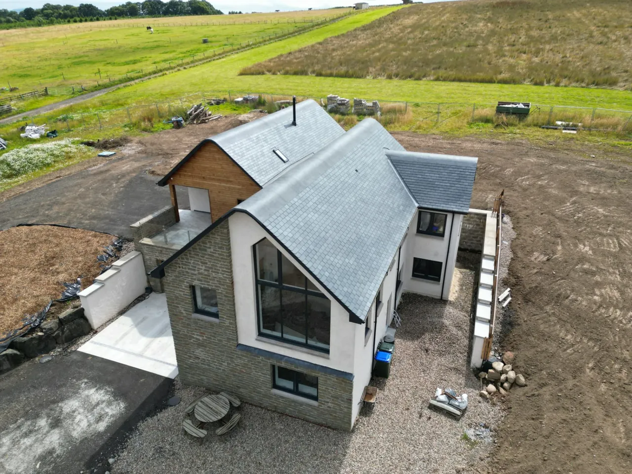 New slate roof over a stone and render gable with a large glazed window